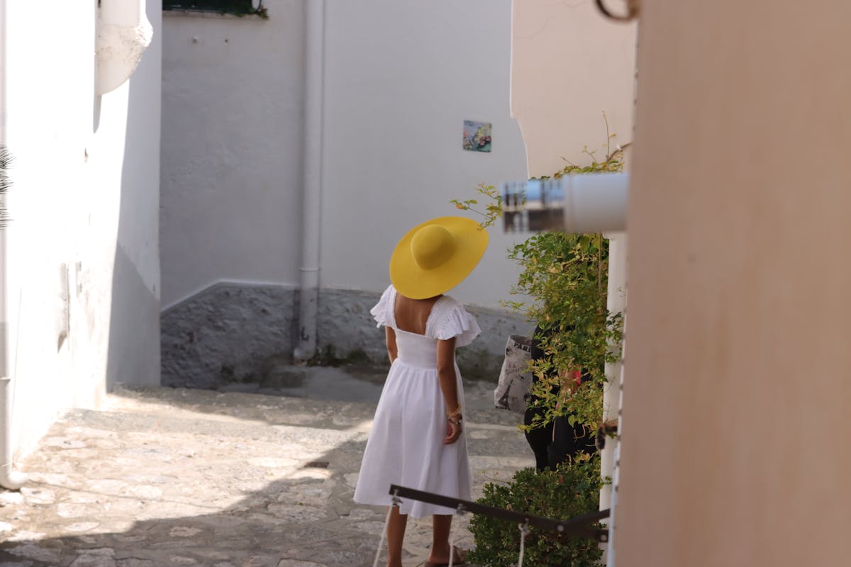 White linen dress with straw hat in a whitewashed Positano alley