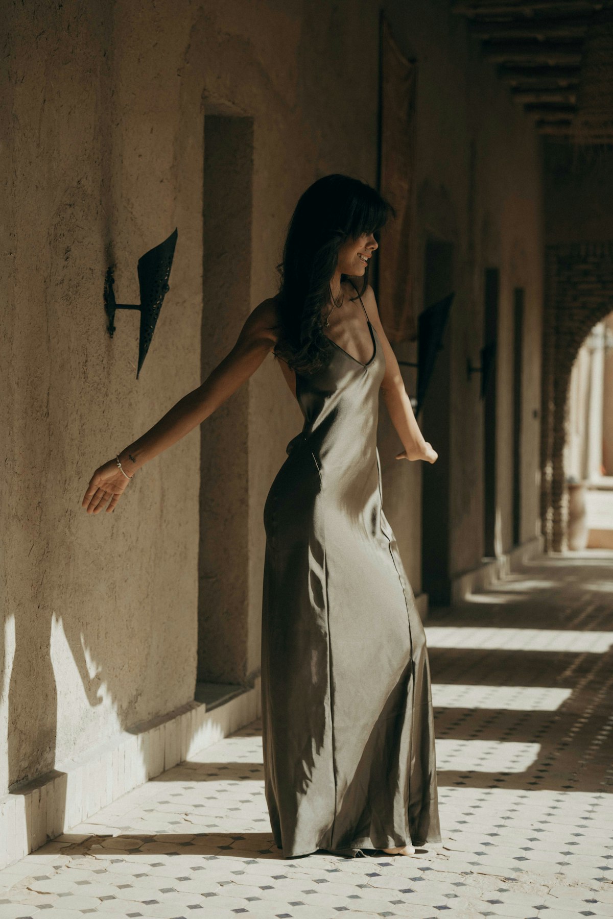 Silk slip dress worn in sunlit arcade